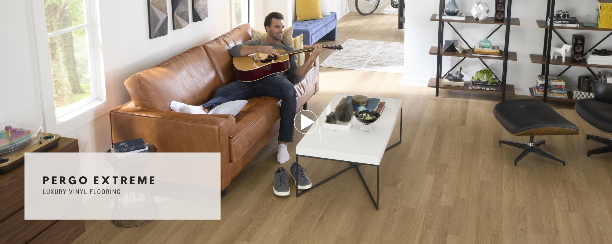 Pergo Extreme Banner featuring a man in an open living room playing a guitar on a leather sofa